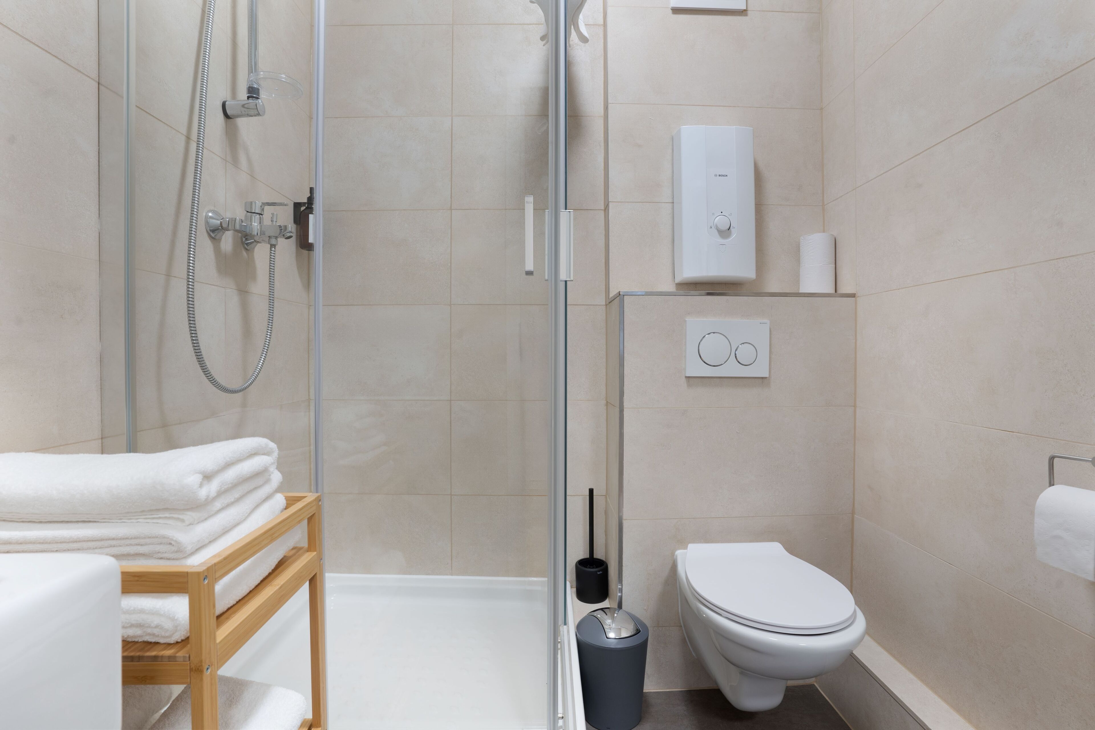 Un baño moderno con cabina de ducha de vidrio, inodoro y perchero para toallas.