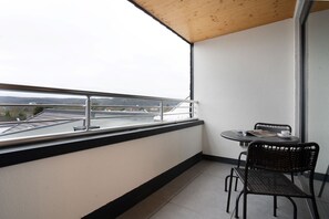 Un balcon avec une table et des chaises, une vue sur un pont et une balustrade.