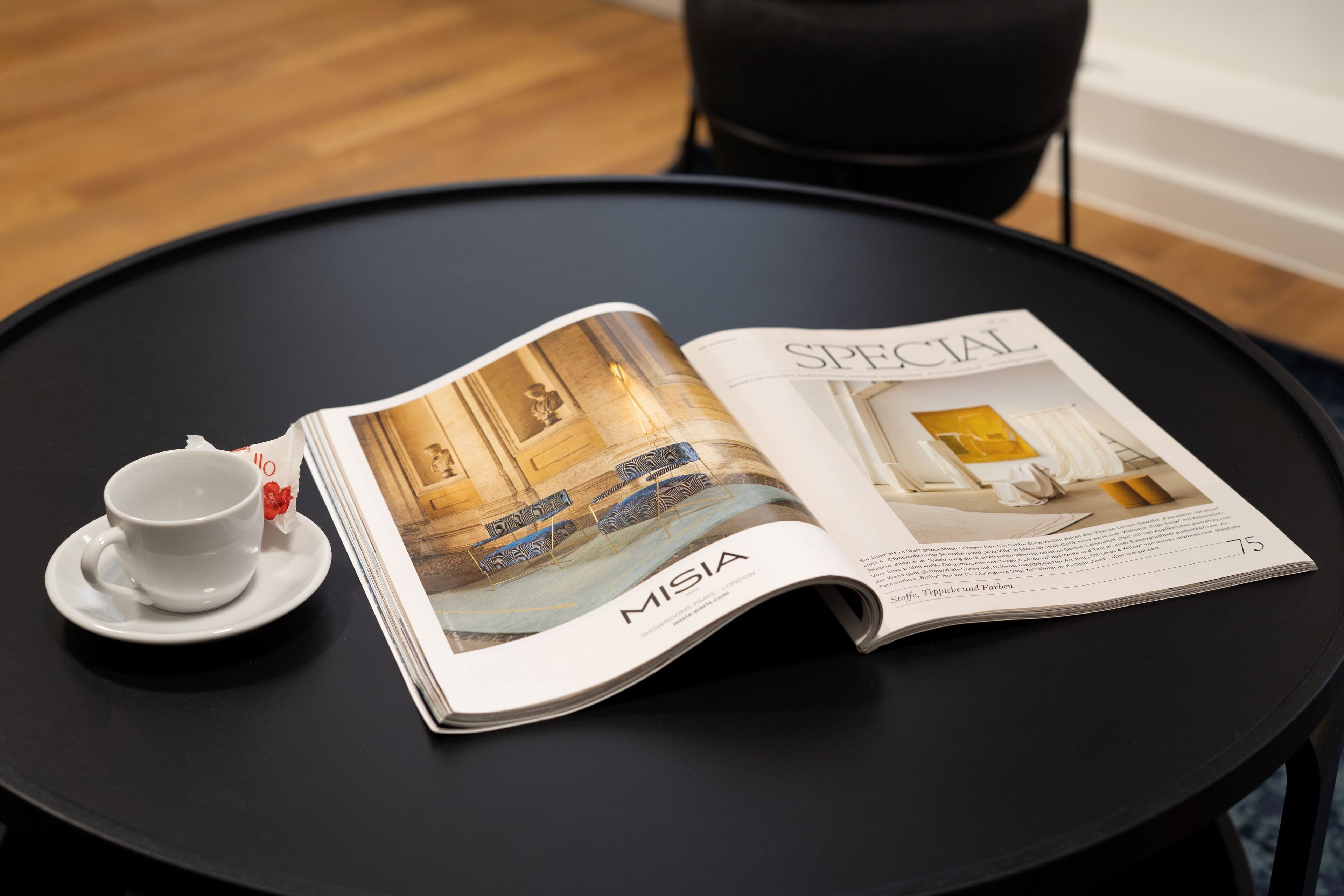 Un magazine ouvert sur une table noire, avec en première page un article intitulé « MISIA » et une tasse avec sa soucoupe.