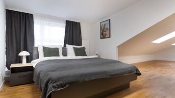 Une chambre à coucher avec un lit, une table de chevet, une lampe et une fenêtre avec des rideaux.