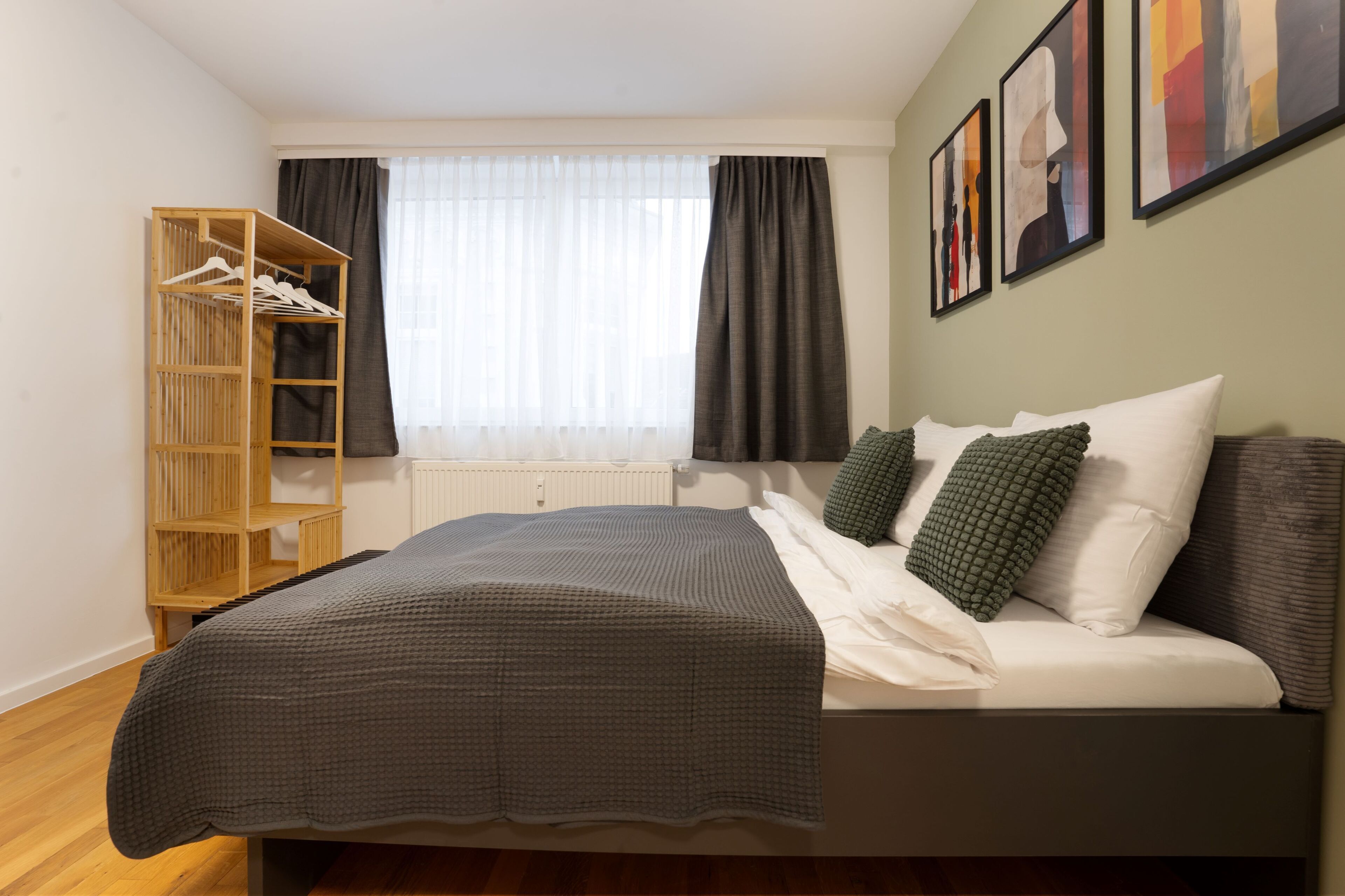 A bedroom with a bed, a wardrobe, and a window with curtains.