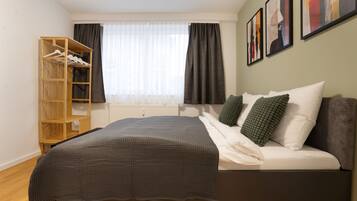 A bedroom with a bed, a wardrobe, and a window with curtains.