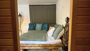 A bedroom with a bed, pillows, a Buddha statue, and a nightstand.