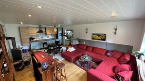 A modern living room with a red sofa, wooden coffee table, and a kitchen in the background.