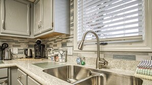 A kitchen with two stainless steel sinks, a coffee maker, and a window with blinds. - 13419 - 19 Aldaya Lane (Hot Springs)