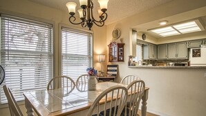A dining area with a wooden table and chairs, a chandelier, and a clock on the wall. - 13419 - 19 Aldaya Lane (Hot Springs)