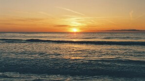 A sunset over the ocean with calm waves.