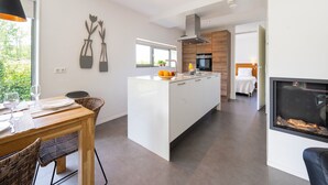A modern kitchen with a central island, a dining area with a table and chairs, and a living space with a fireplace.