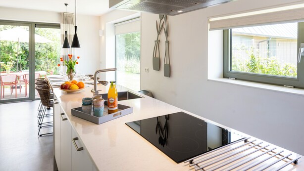 A modern kitchen with a central island, a built-in stove, and a large window.