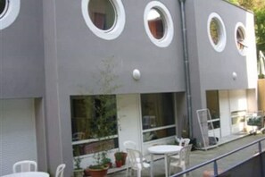 A modern building with circular windows and a balcony with white chairs and tables. - Townhouse n°3 TVA Grenoble city center (Grenoble)
