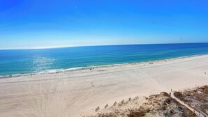A wide sandy beach with clear blue water and a bright sun. - Summer House 901B by Liquid Life (Orange Beach)