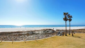 A beach with a clear sky, a sandy shore, and a few palm trees. - Summer House 203B by Liquid Life (Orange Beach)