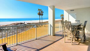 A balcony with a view of the beach and ocean, a table and chairs, and a door to the right. - Summer House 203B by Liquid Life (Orange Beach)