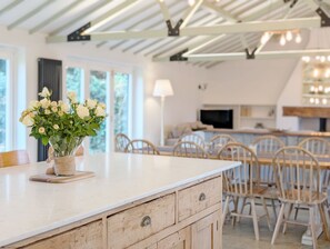 A modern kitchen with wooden cabinetry, a marble countertop, and a vase of white flowers.