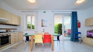 A modern kitchen with wooden cabinets, a gas stove, and a dining area with a table and chairs. - Ibiscus-Iblee, holiday home with garden 100 mt from the sea (Marina di Ragusa)