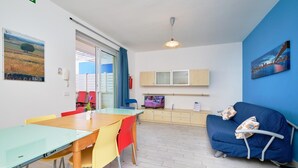 A modern living room with a dining area, a sofa, and a TV. - Ibiscus-Iblee, holiday home with garden 100 mt from the sea (Marina di Ragusa)
