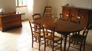 Ein Essbereich mit Holztisch, sechs Stühlen, einem Holzschrank und einem Fenster mit Vorhängen.
