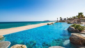 A clear blue pool with a beach view, surrounded by palm trees and lounge chairs. - Luxurious/comfortable 2-bdrm, 3 bath resort/spa in enchanting San Jose de Cabo (San Jose de Cabo)