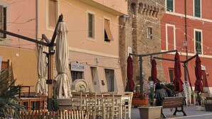 Espace extérieur avec des tables et des parasols, un bâtiment en pierre et une enseigne indiquant « OTTO ZERO ».