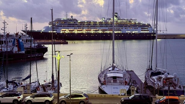 Un navire de croisière était amarré dans une marina où l’on pouvait voir de nombreux bateaux et des voitures.
