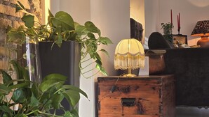 Une pièce chaleureuse avec une commode en bois, une plante en pot, une lampe et un mur au motif de briques.