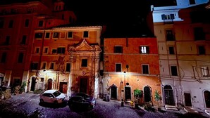 Vue nocturne d’une rue historique bordée d’immeubles à l’architecture classique, dont un bâtiment central doté d’une façade ornée et de fenêtres en arc de cercle.