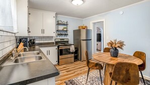 Una cocina moderna con armarios blancos, electrodomésticos de acero inoxidable y una mesa de comedor de madera con sillas.