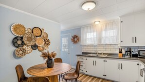 Una cocina moderna con armarios blancos, una mesa de comedor de madera y varios platos decorativos en la pared.
