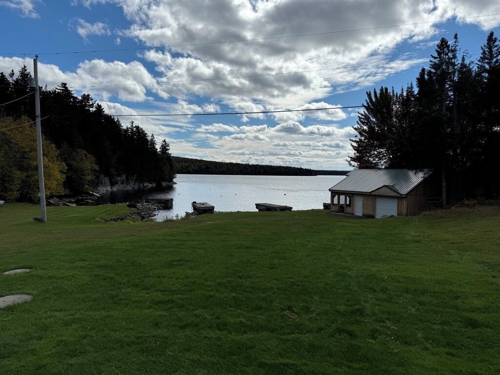 Un área verde con un pequeño edificio y un muelle junto a un lago.