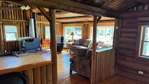 Een rustiek houten interieur met een open haard, een bank en een eethoek.