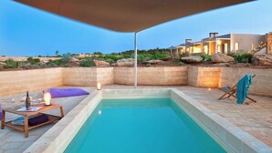 Una piscina con una mesa de madera y una silla, una toalla y una lámpara.