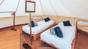 A tent with two wooden beds, each with pillows and blankets, and a woven basket on the floor. - Lodging Nature Camp Crozon  (Lanveoc)