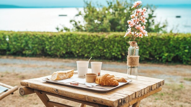 A wooden picnic table with croissants, coffee cups, and a jar with flowers. - Lodging Nature Camp Crozon  (Lanveoc)