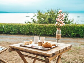 A wooden picnic table with croissants, coffee cups, and a jar with flowers. - Lodging Nature Camp Crozon  (Lanveoc)