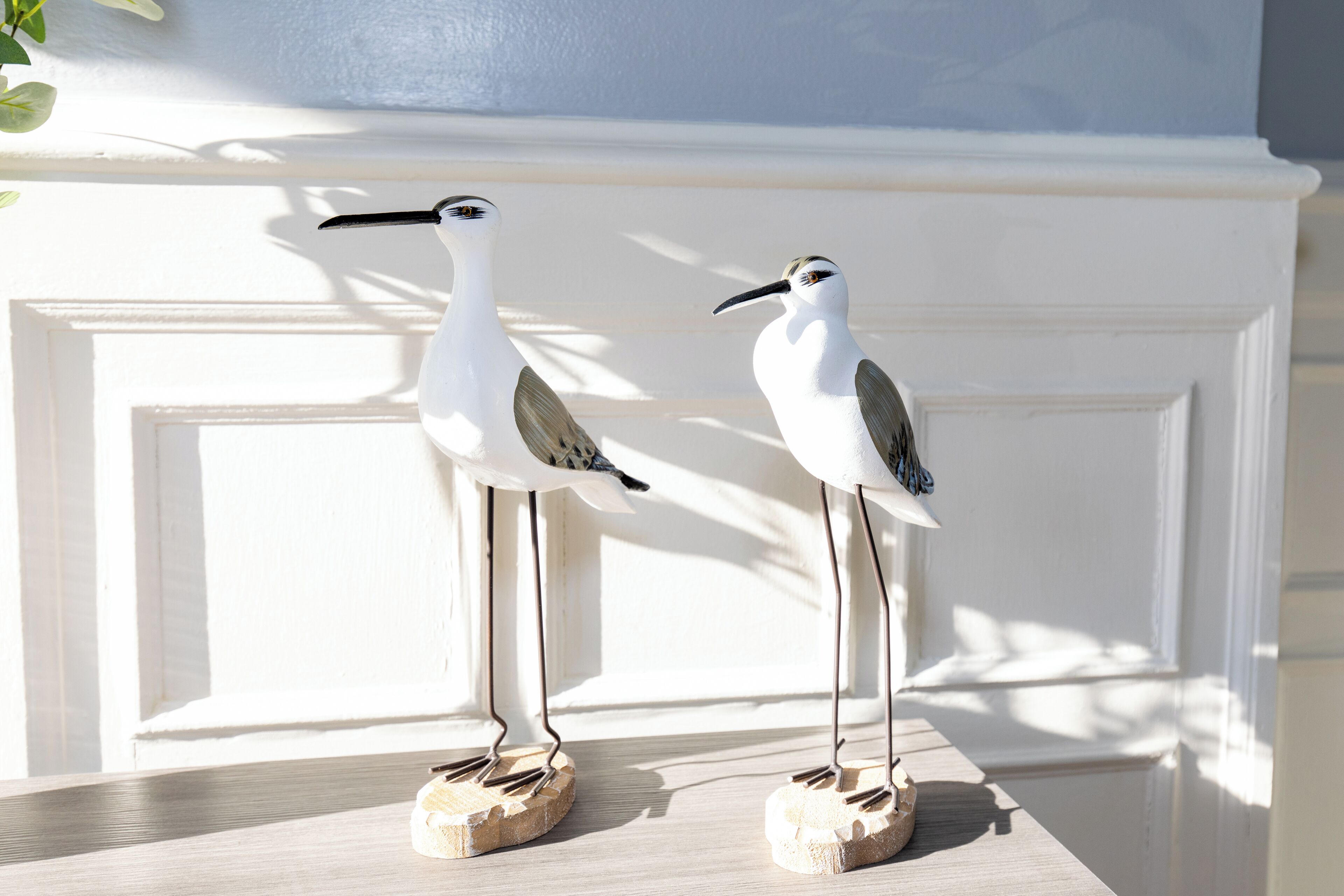 Two bird-shaped sculptures on a wooden surface.