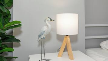 Ein weißer Nachttisch mit Lampe und einer dekorativen Vogel-Skulptur.