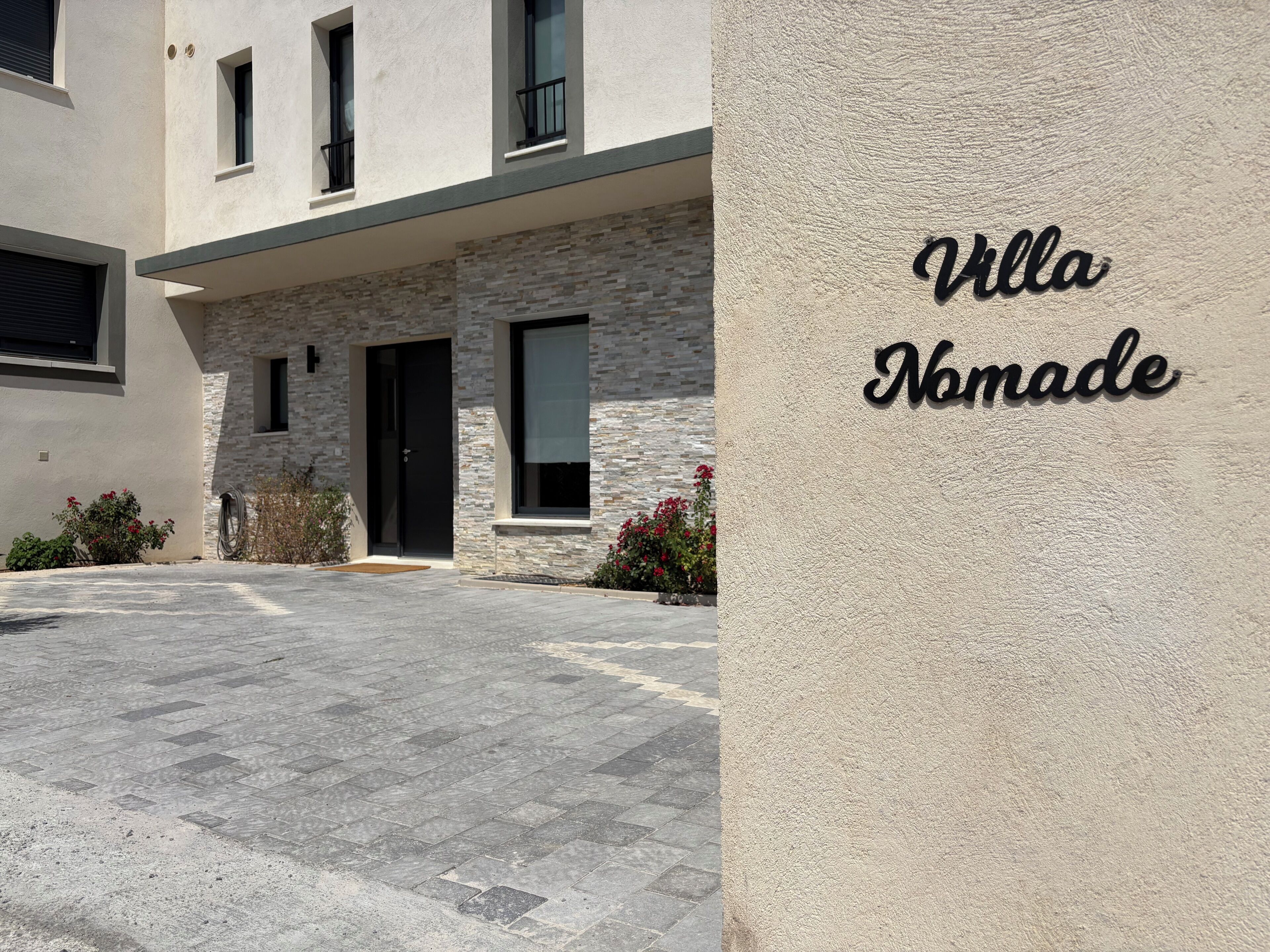 A modern building with a stone facade, a black door, and a sign that reads 'Villa Nomade.'