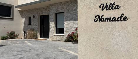 A modern building with a stone facade, a black door, and a sign that reads 'Villa Nomade.'
