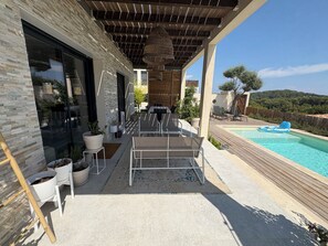 A modern outdoor patio with a pool, seating area, and potted plants.