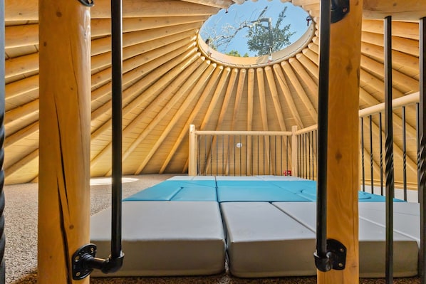 Une yourte dotée d’une lucarne circulaire, de sièges rembourrés et offrant une vue sur l’extérieur.