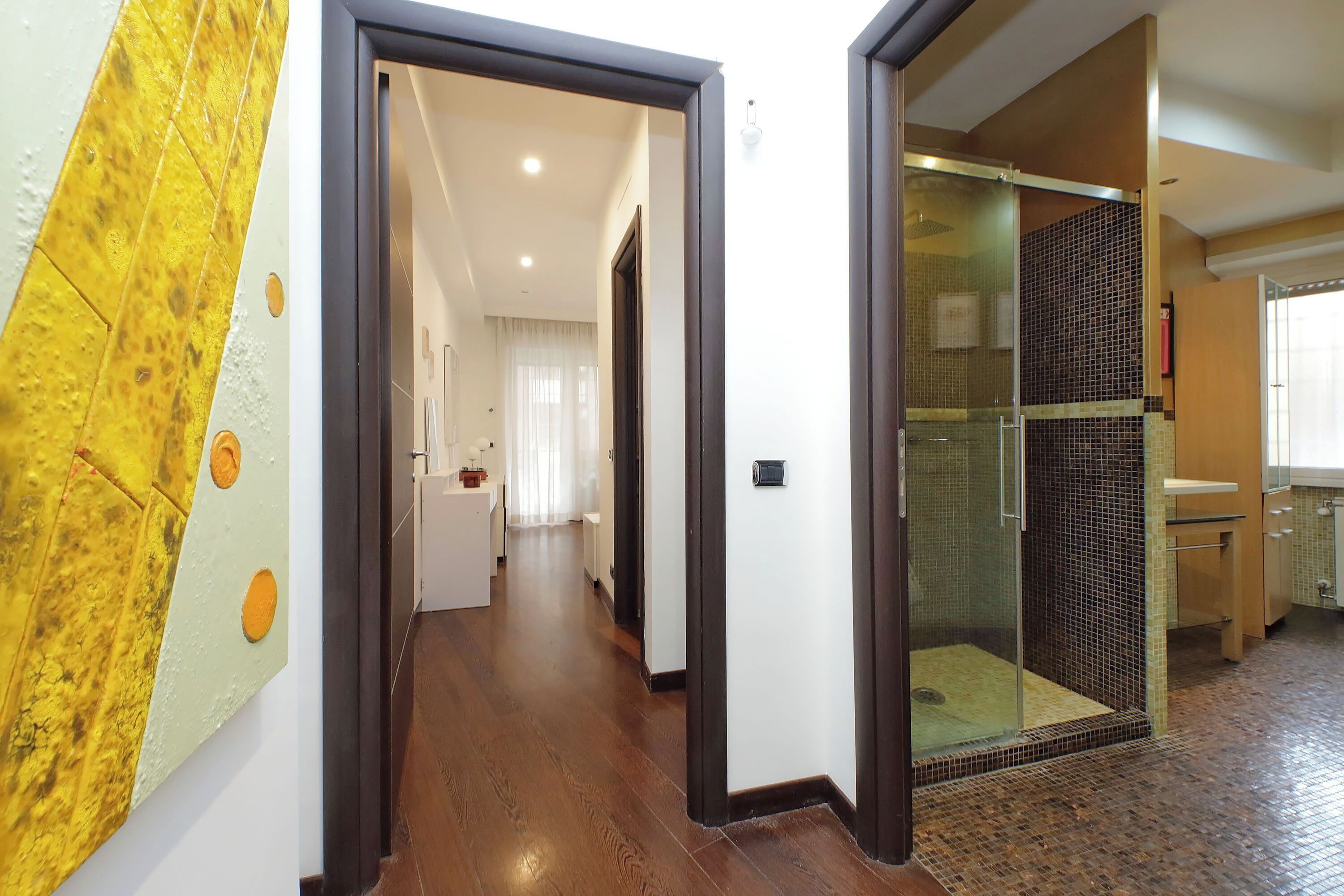 Corridoio che conduce a un bagno con box doccia in vetro.