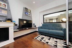 Ein Wohnzimmer mit Flachbildfernseher, blauem Sofa, gemustertem Teppich und Kamin.