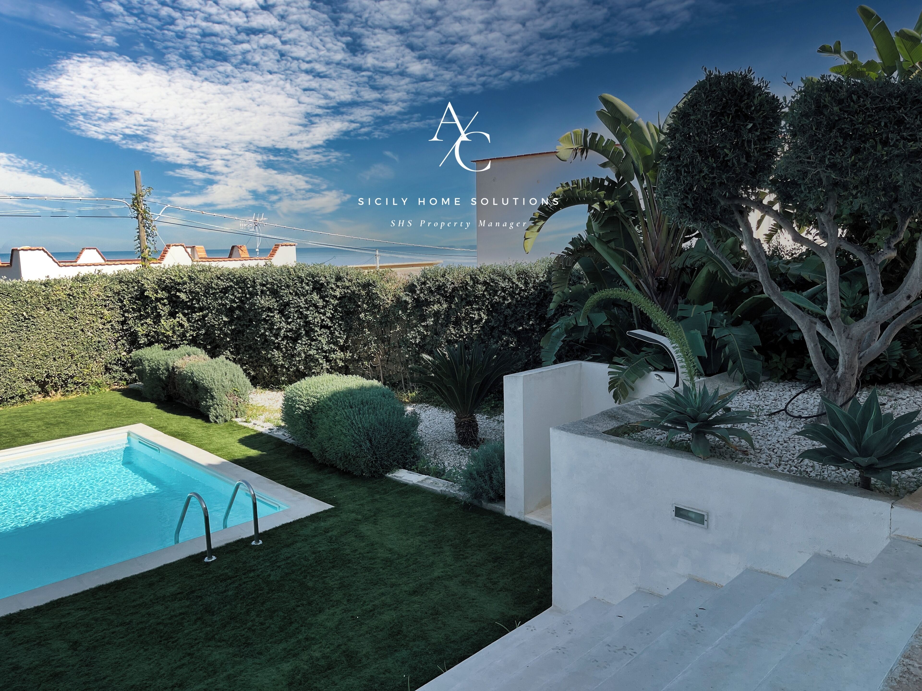 A modern outdoor pool area with a clear view of the sea in the background.