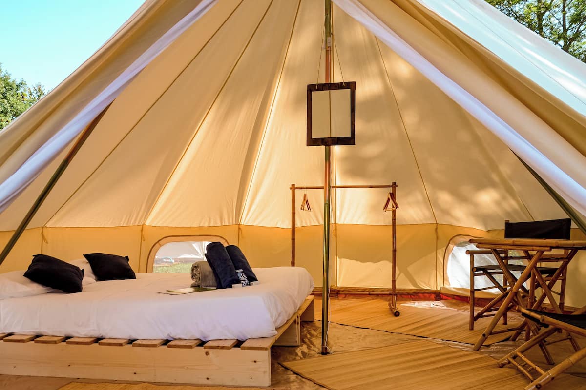 Una carpa con cama, una mesa y un lámpara colgante.