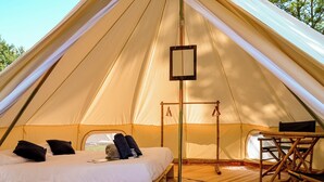 Una carpa con cama, una mesa y un lámpara colgante.