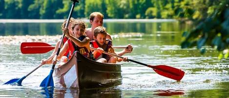 Un grupo de personas en una canoa sobre un lago tranquilo rodeado de abundante vegetación.