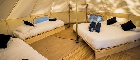 A tent with two beds, each with pillows and towels.