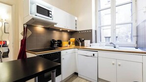A modern kitchen with white cabinets, a microwave, a coffee maker, and a window providing natural light. - Historic loft with character, Grenoble city center (Grenoble)