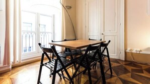 A dining area with a wooden table and black metal chairs, a white door, and a window with a view of buildings. - Historic loft with character, Grenoble city center (Grenoble)