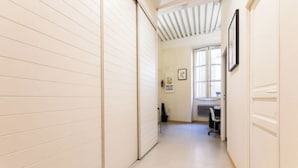 A narrow hallway with white walls and a tiled floor, leading to a room with a desk and chair. - Historic loft with character, Grenoble city center (Grenoble)